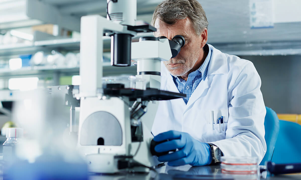 Homme qui regarde dans microscope en laboratoire