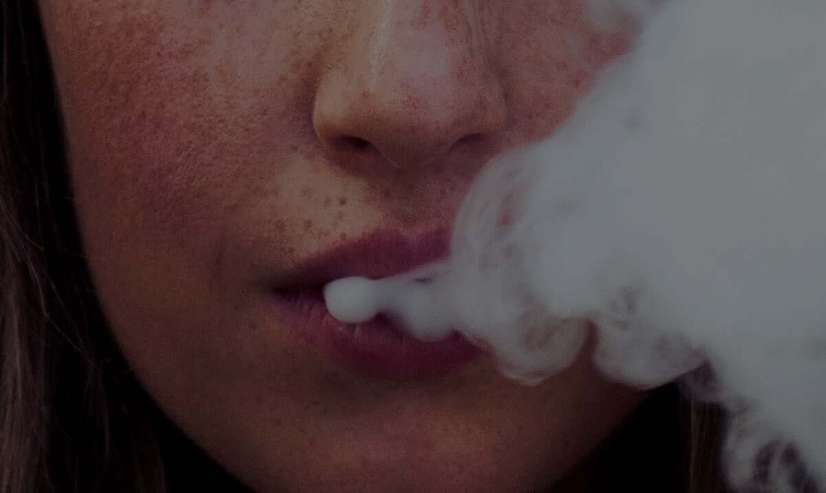 Gros plan sur une femme qui expulse de la fumée par la bouche